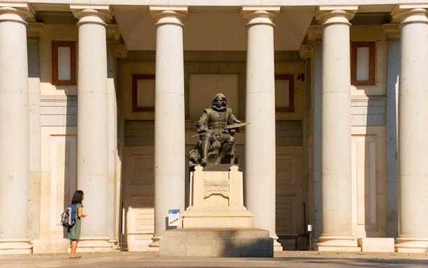 Tourist at Velázquez statue outside Prado Museum, Madrid.