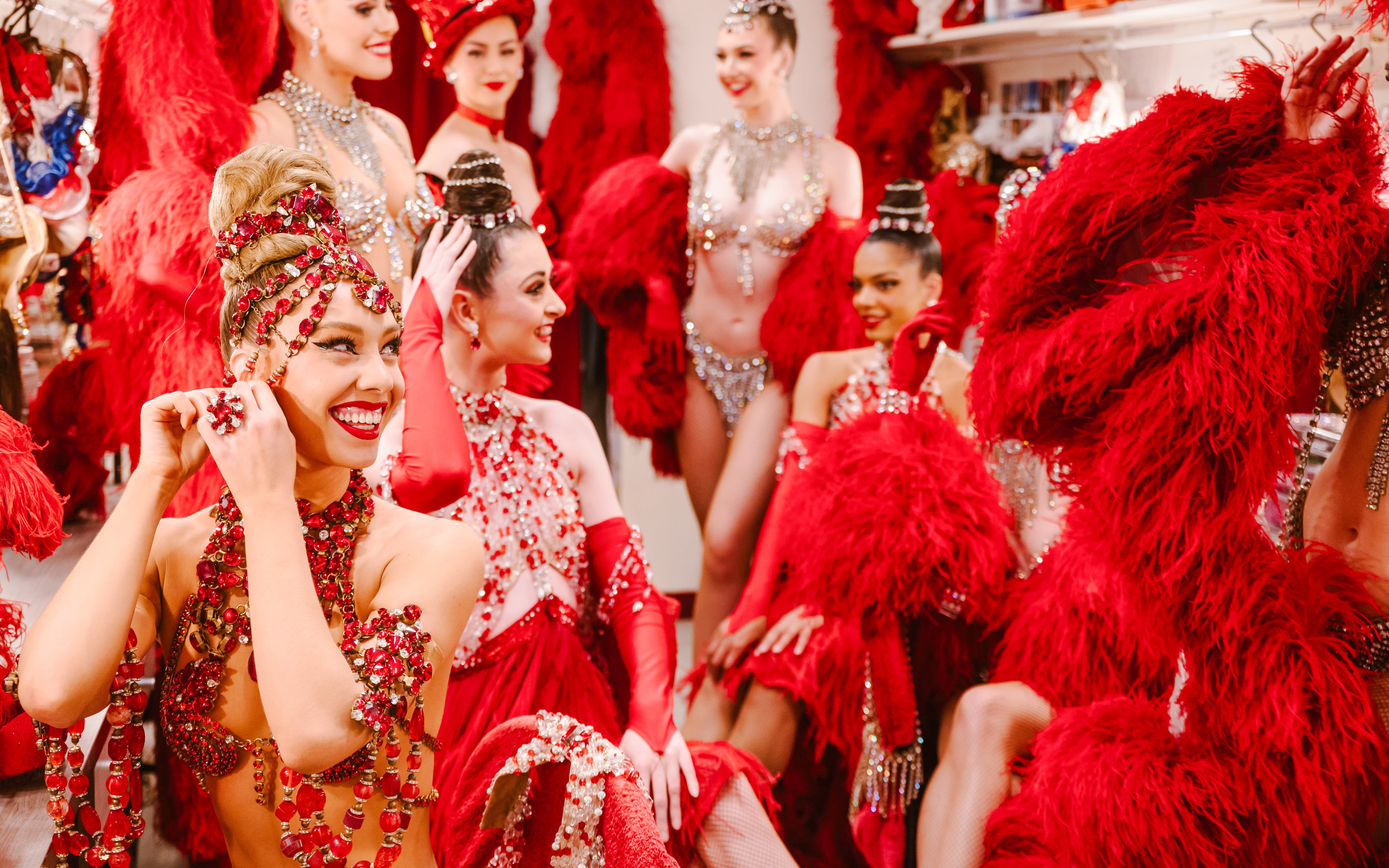 Performers in red costumes preparing backstage for the Moulin Rouge Show in Paris.