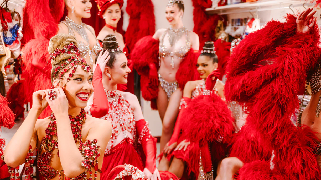 Performers in red costumes preparing backstage for the Moulin Rouge Show in Paris.