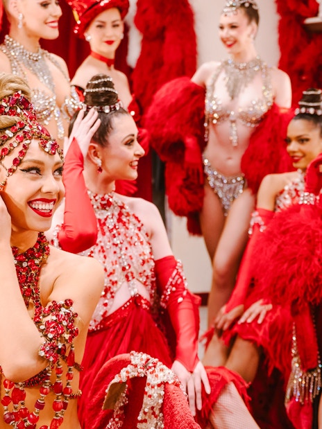 Performers in red costumes preparing backstage for the Moulin Rouge Show in Paris.