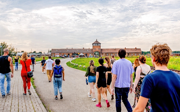 Visitors walking towards the entrance gate of Auschwitz II, Auschwitz-Birkenau on a guided tour.