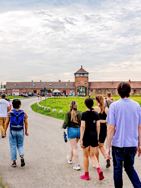 Visitors walking towards the entrance gate of Auschwitz II, Auschwitz-Birkenau on a guided tour.