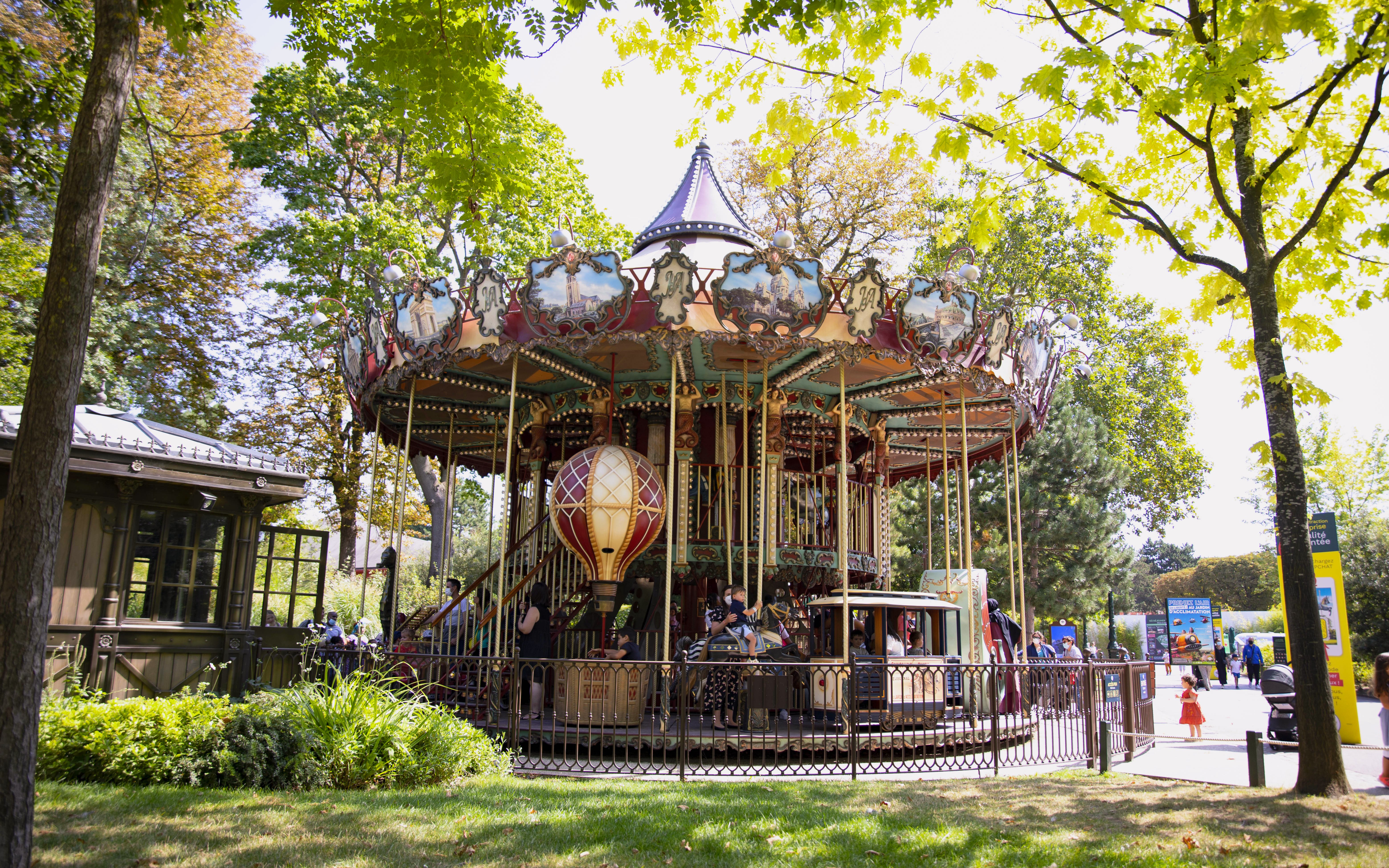 Carousel ride at Le Jardin d'Acclimatation in Paris surrounded by trees.