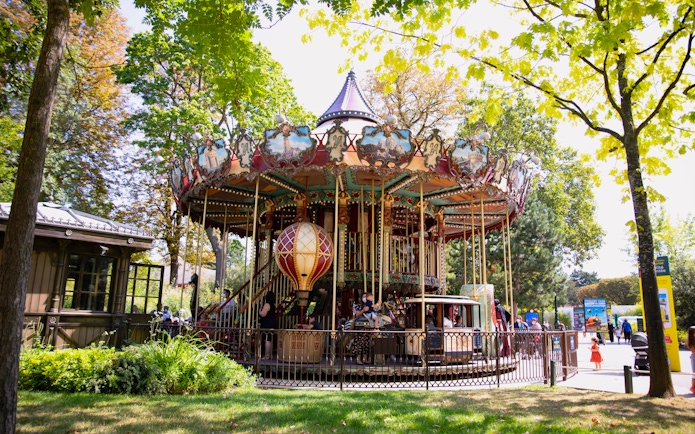 Carousel ride at Le Jardin d'Acclimatation in Paris surrounded by trees.