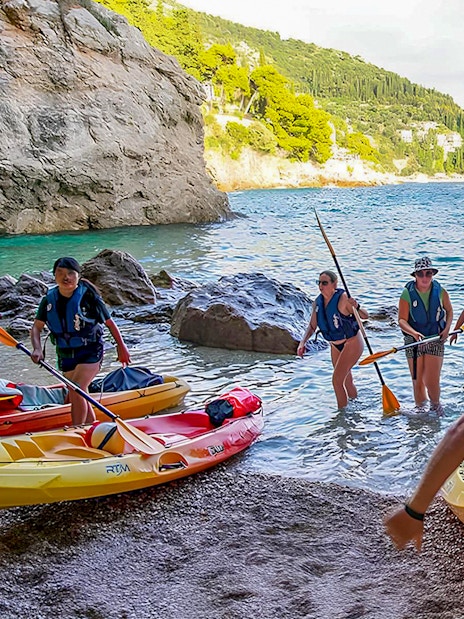 Kayakers arriving at rocky shore in Dubrovnik during morning tour.