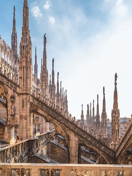 Visitors exploring the rooftop terrace of Milan Duomo Cathedral with spires in view.