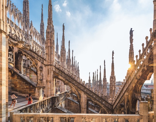 Visitors exploring the rooftop terrace of Milan Duomo Cathedral with spires in view.