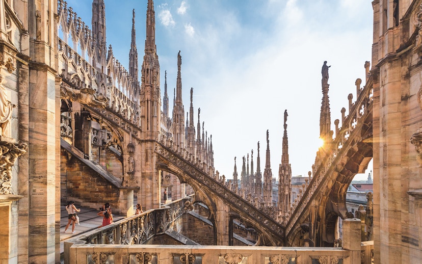 Visitors exploring the rooftop terrace of Milan Duomo Cathedral with spires in view.
