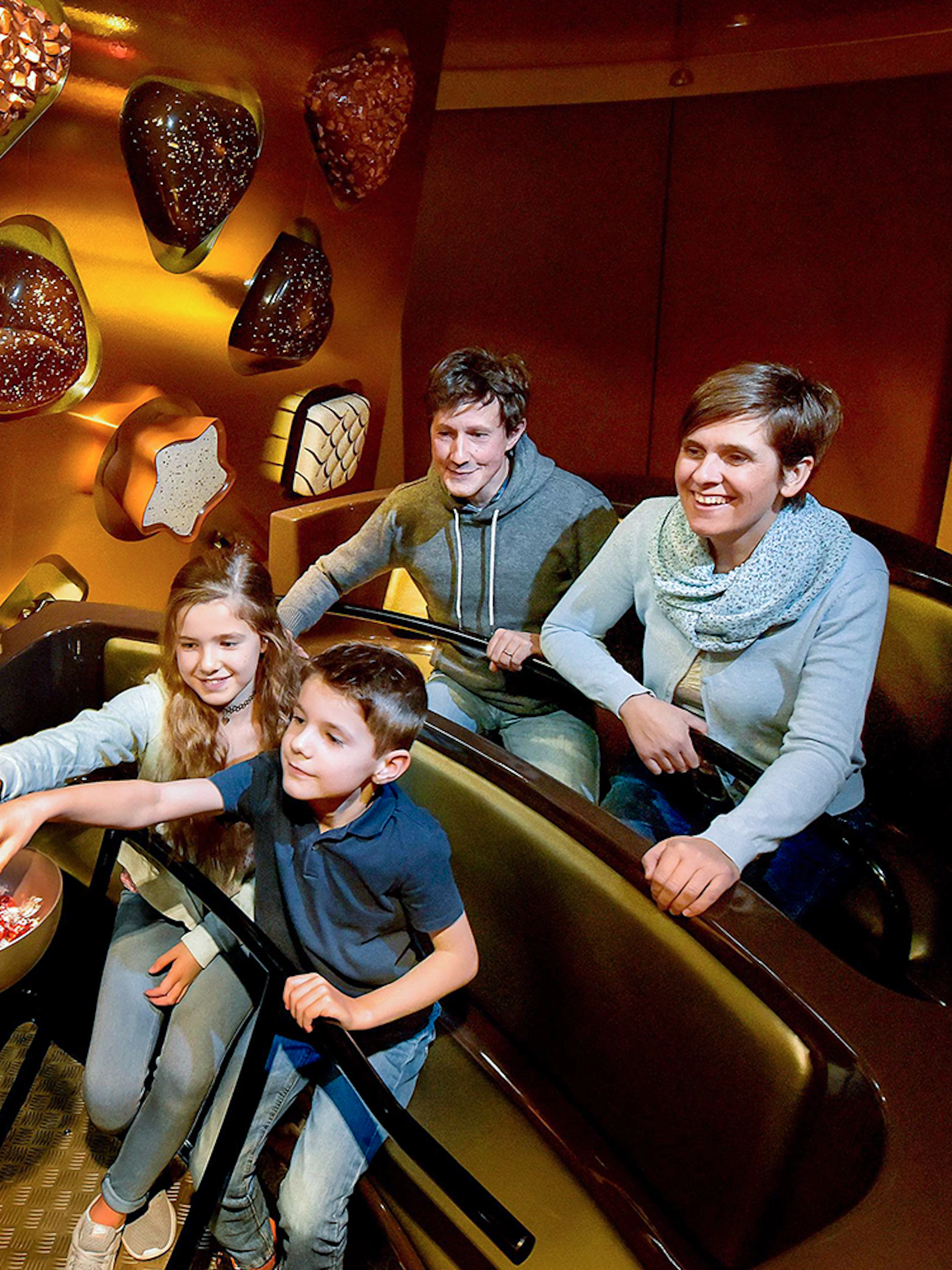Kids selecting chocolates from a bowl at Swiss Chocolate Adventure, Lucerne.