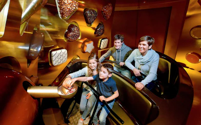 Kids selecting chocolates from a bowl at Swiss Chocolate Adventure, Lucerne.