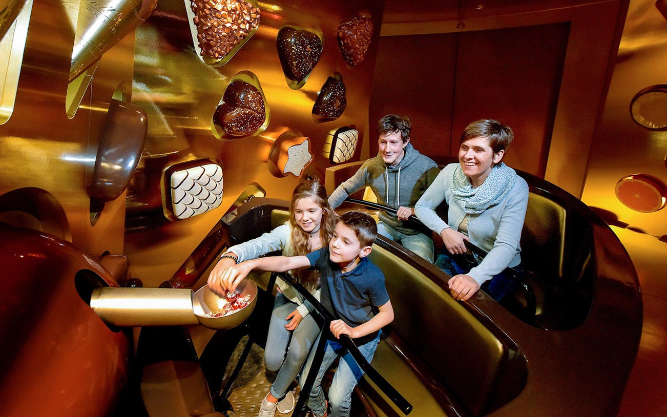Kids selecting chocolates from a bowl at Swiss Chocolate Adventure, Lucerne.