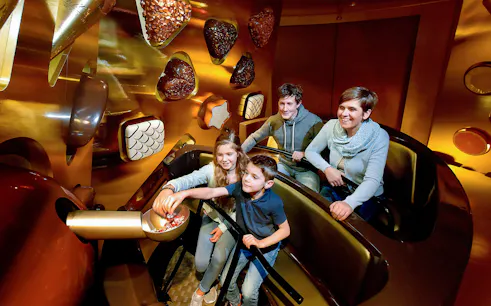 Kids selecting chocolates from a bowl at Swiss Chocolate Adventure, Lucerne.