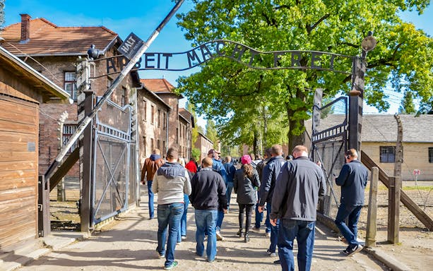 Visitors entering through the Arbeit macht frei gate at Auschwitz Birkenau, Krakow.