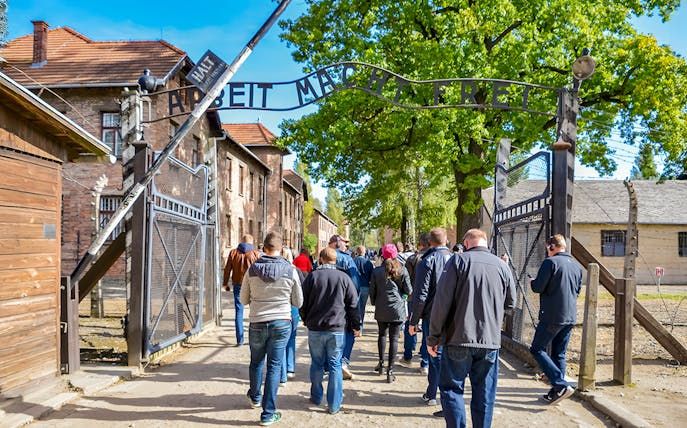 Visitors entering through the Arbeit macht frei gate at Auschwitz Birkenau, Krakow.
