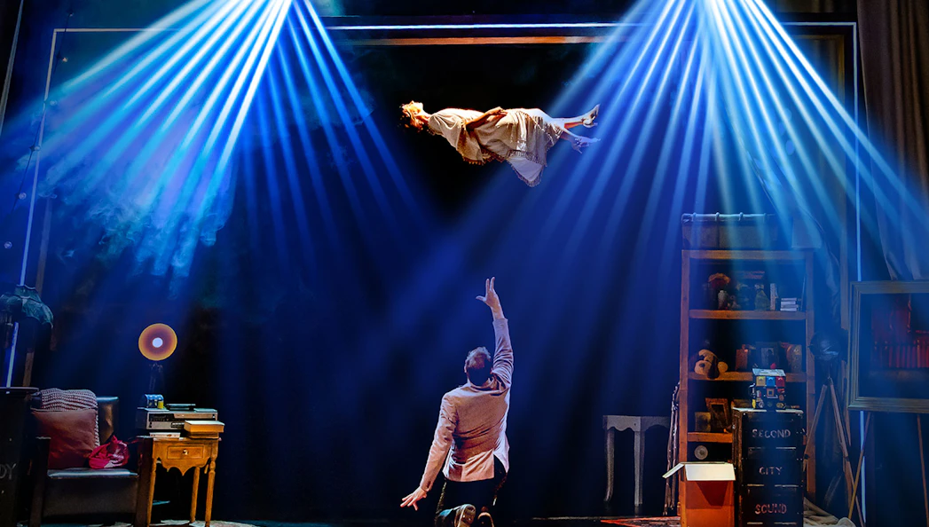 Performer levitating in Jamie Allan's Amaze theatre act with dramatic lighting.