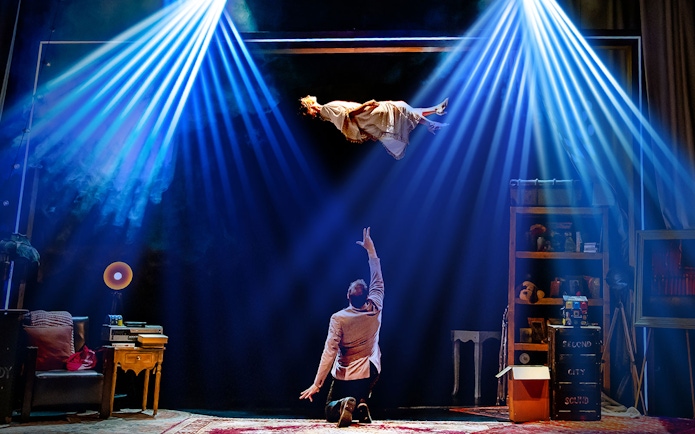 Performer levitating in Jamie Allan's Amaze theatre act with dramatic lighting.