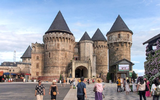 Stone castle towers at Ba Na Hills with tourists exploring the courtyard.