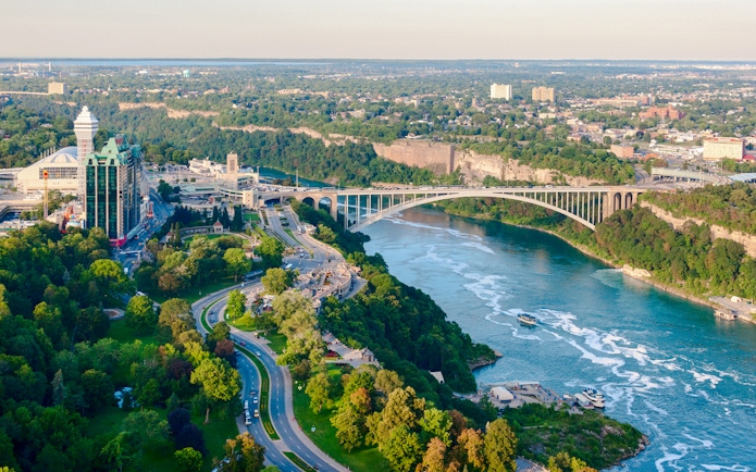Rainbow Bridge spanning Niagara River on Niagara Parkway, with surrounding greenery and cityscape.
