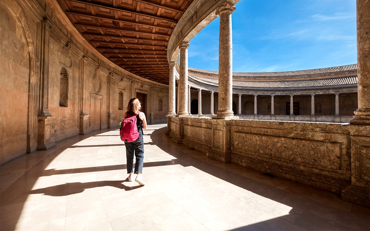 Tourist walking through the Alhambra palace courtyard in Granada, Spain.
