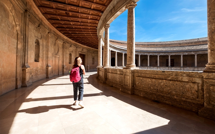 Tourist walking through the Alhambra palace courtyard in Granada, Spain.