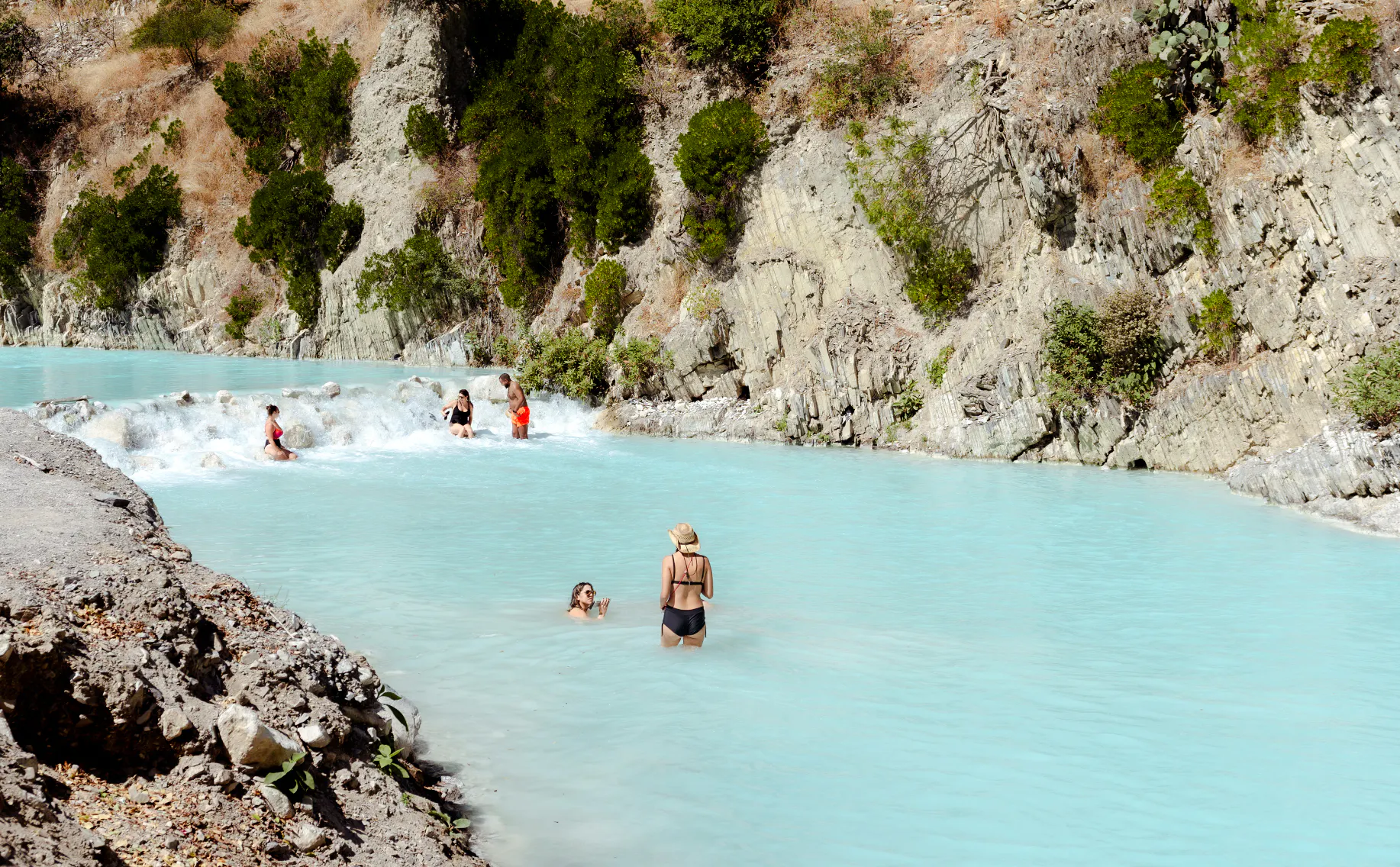 Visitors enjoying Tolantongo Hot Springs' turquoise waters, surrounded by rocky cliffs.