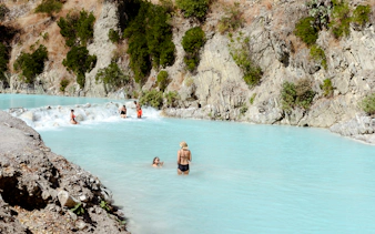 Visitors enjoying Tolantongo Hot Springs' turquoise waters, surrounded by rocky cliffs.