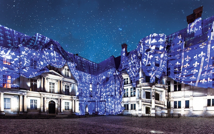 Sound and Light Show at Royal Château of Blois with illuminated facade and starry sky.