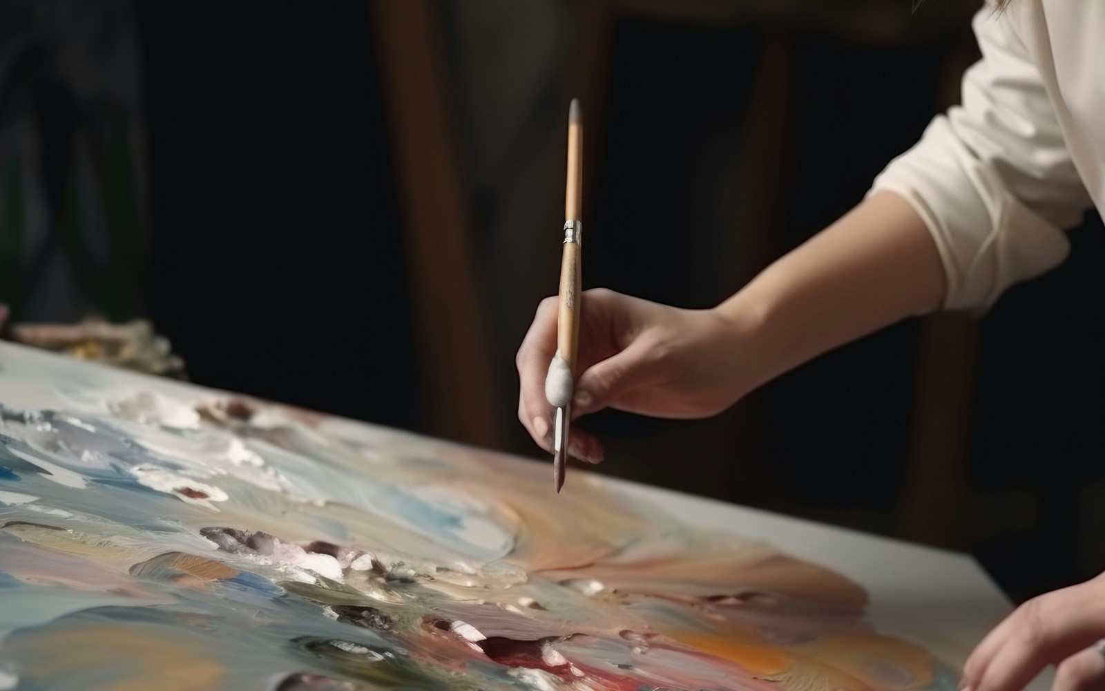 Artist's hand painting with a brush on a colorful canvas.
