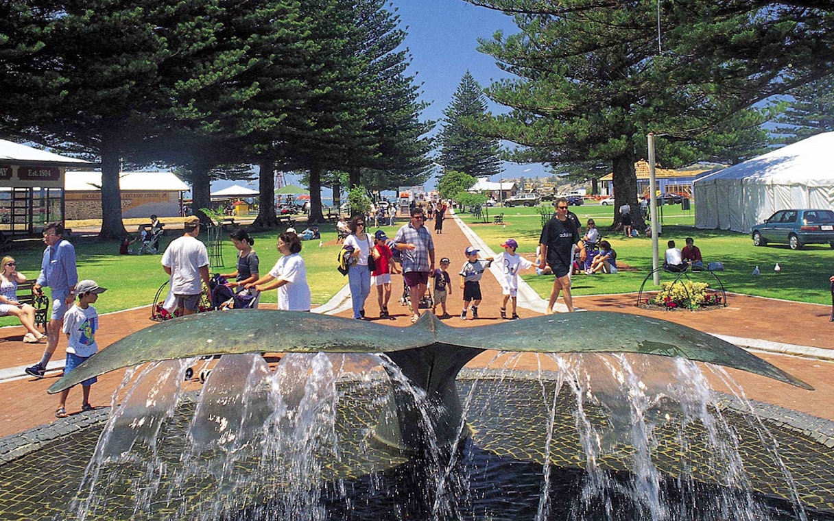 Fountain and people in a park at Victor Harbor, Australia, with trees and tents in the background.