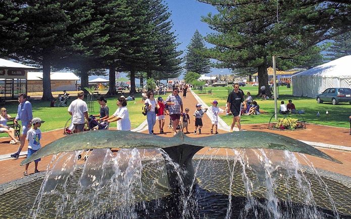 Fountain and people in a park at Victor Harbor, Australia, with trees and tents in the background.