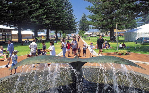 Fountain and people in a park at Victor Harbor, Australia, with trees and tents in the background.