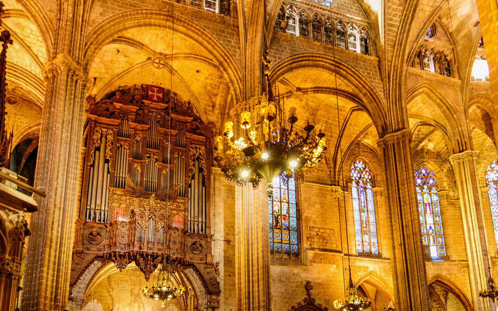 Interior of the Cathedral of Barcelona with ornate organ and stained glass windows.
