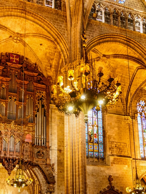 Interior of the Cathedral of Barcelona with ornate organ and stained glass windows.