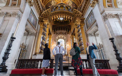 Visitors inside St Paul's Cathedral, London, admiring ornate columns and stained glass.