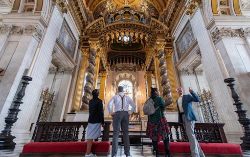 Visitors inside St Paul's Cathedral, London, admiring ornate columns and stained glass.
