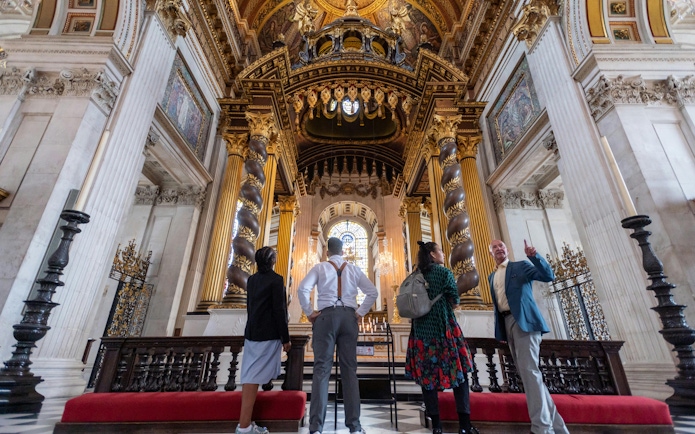 Visitors inside St Paul's Cathedral, London, admiring ornate columns and stained glass.