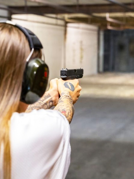 Person aiming a handgun at a target in an indoor shooting range.