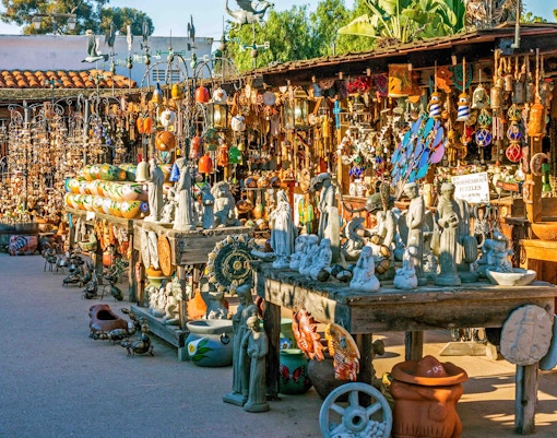 Outdoor market stall with colorful crafts and sculptures in Old Town San Diego.