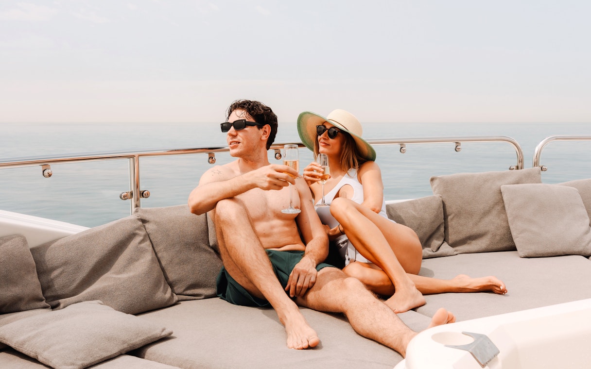 Couple relaxing on a luxury yacht cruise in Dubai, enjoying drinks on deck.