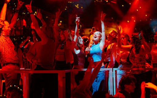 Audience enjoying Mamma Mia! The Party performance with vibrant lights and festive atmosphere.
