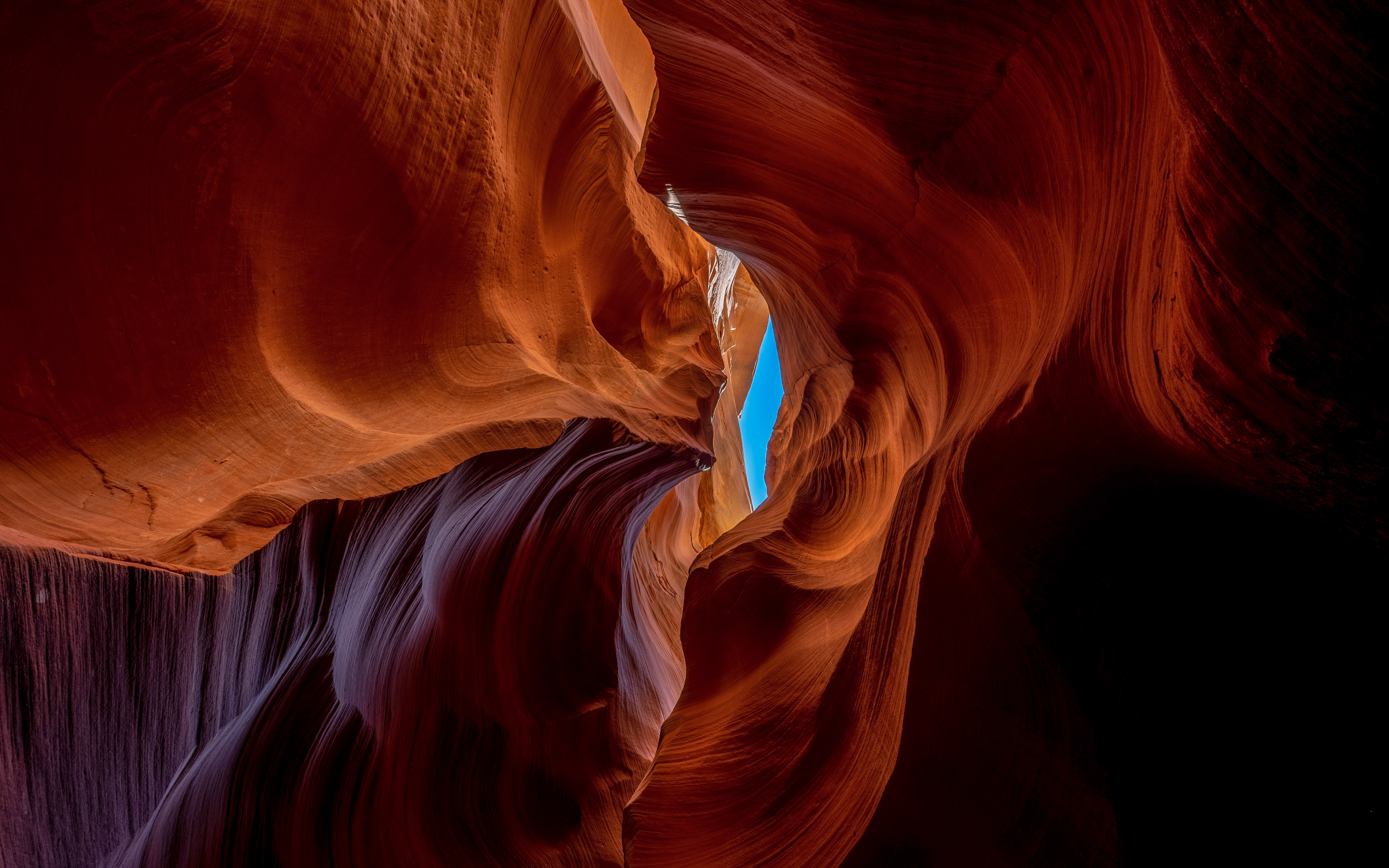 Red sandstone formations in Deer Canyon, Arizona with a view of the sky through a narrow opening.