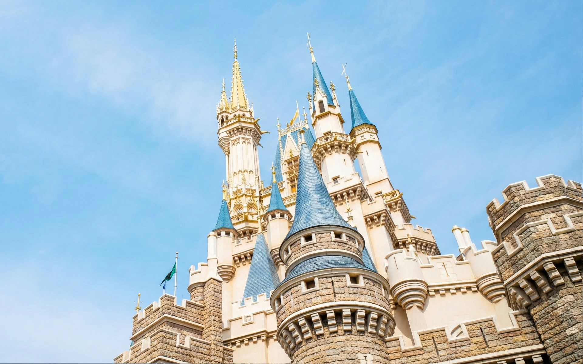 Cinderella Castle spires at Tokyo Disneyland, Japan against blue sky.
