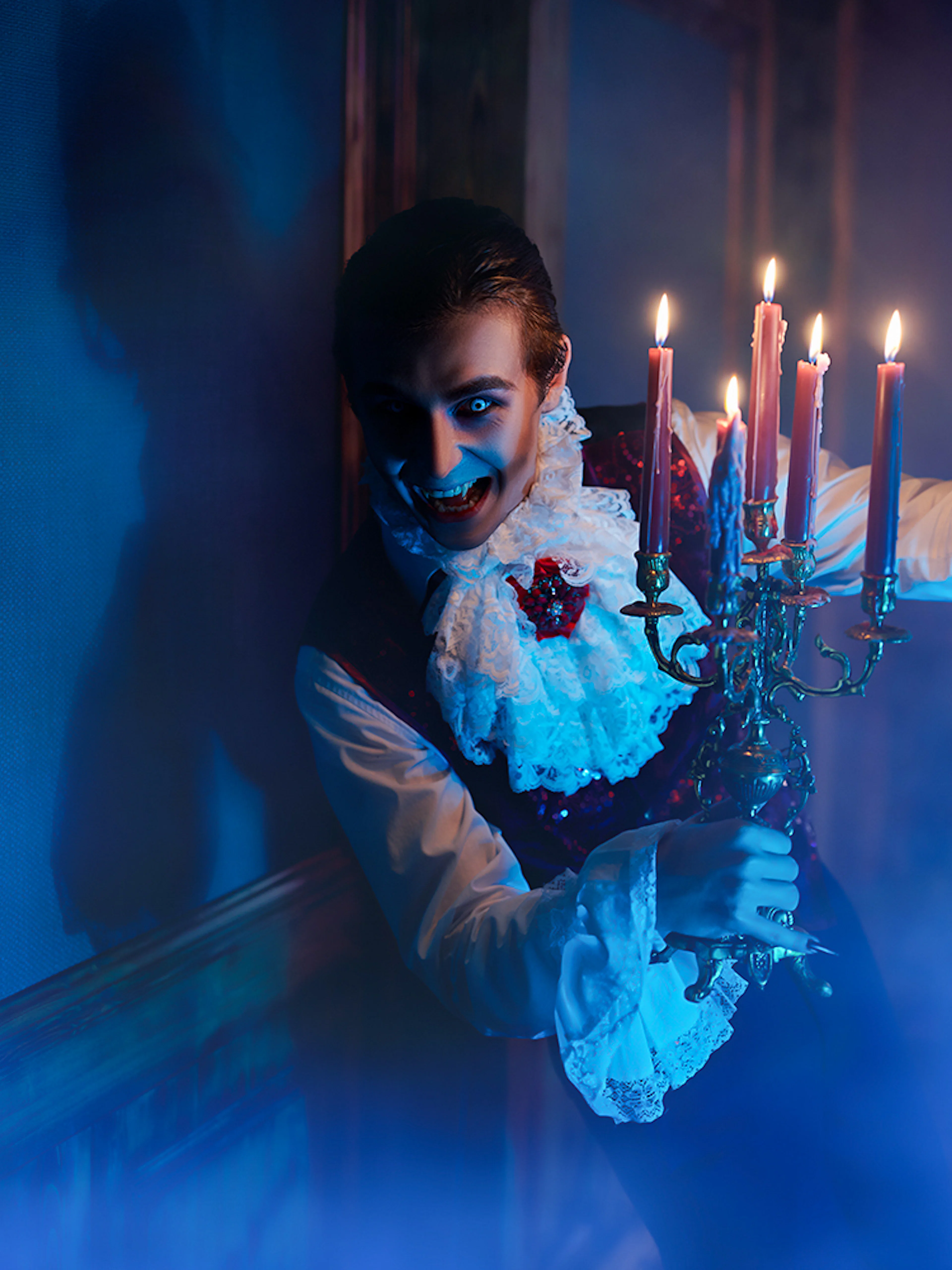 Person in vampire costume holding candelabra at Dracula's Castle Halloween tour.