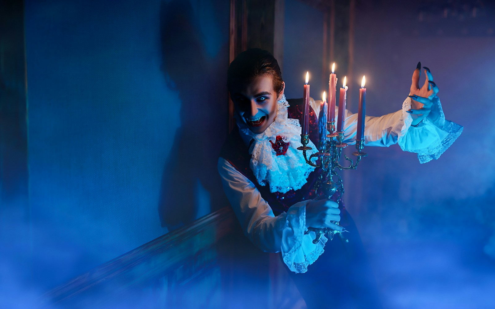 Person in vampire costume holding candelabra at Halloween tour.