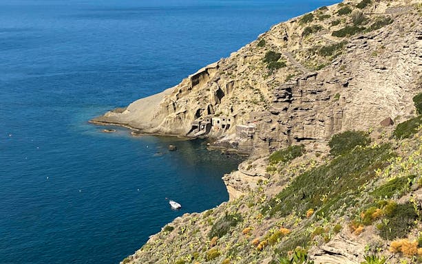 Boat near rocky coastline on Lipari to Salina tour route.