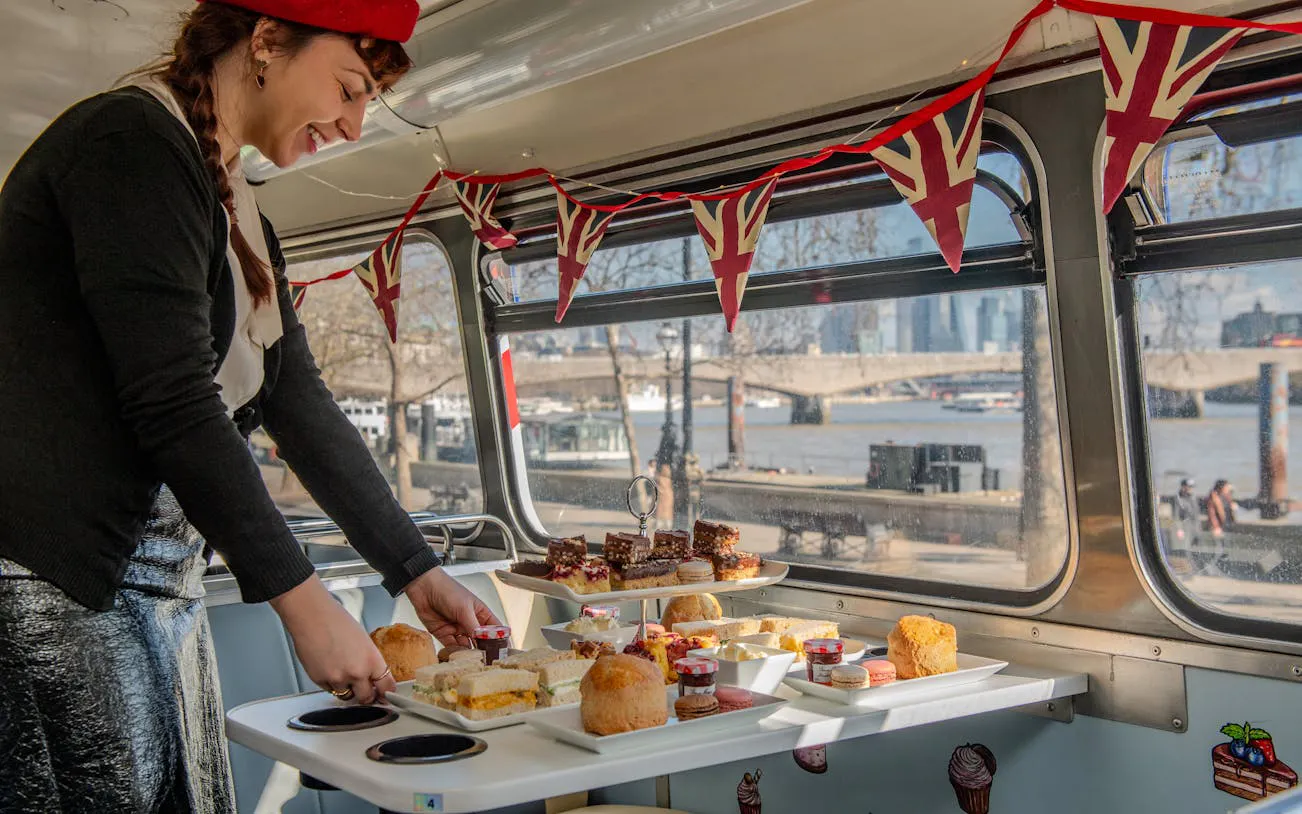 Afternoon tea setup on a bus with view of Central London landmarks.
