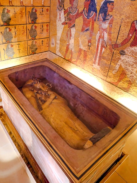 Sarcophagus in Luxor Temple's Valley of the Kings interior with ancient Egyptian wall art.
