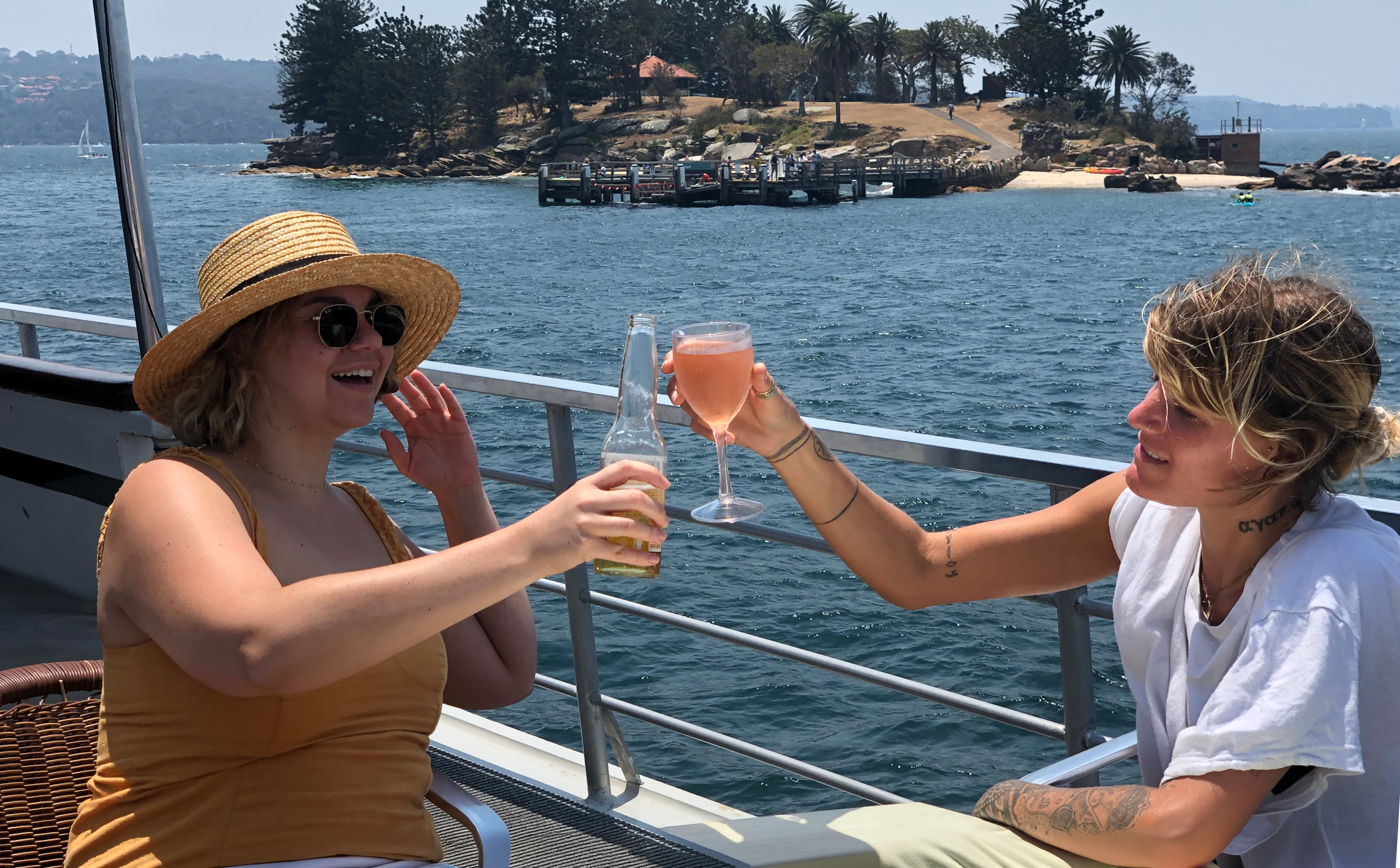 Guests enjoying drinks on a Sydney Harbour luxury dinner cruise with scenic island view.