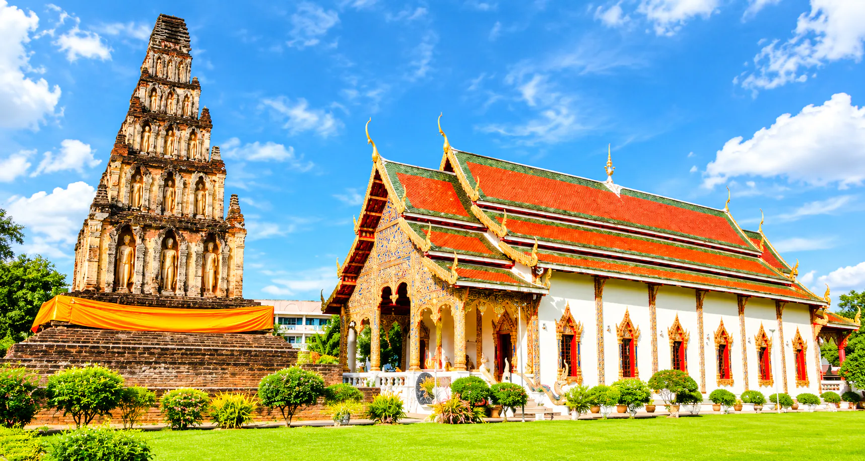 Ancient temple and pagoda in Lamphun, Thailand, under a clear blue sky.