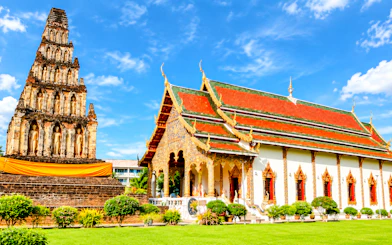Ancient temple and pagoda in Lamphun, Thailand, under a clear blue sky.